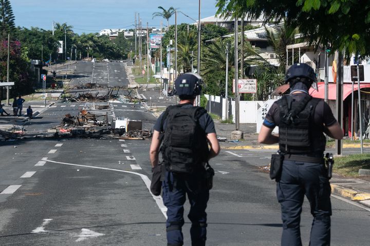 Police patrol a street blocked by debris and burnt out items following overnight unrest in New Caledonia on May 18, 2024.