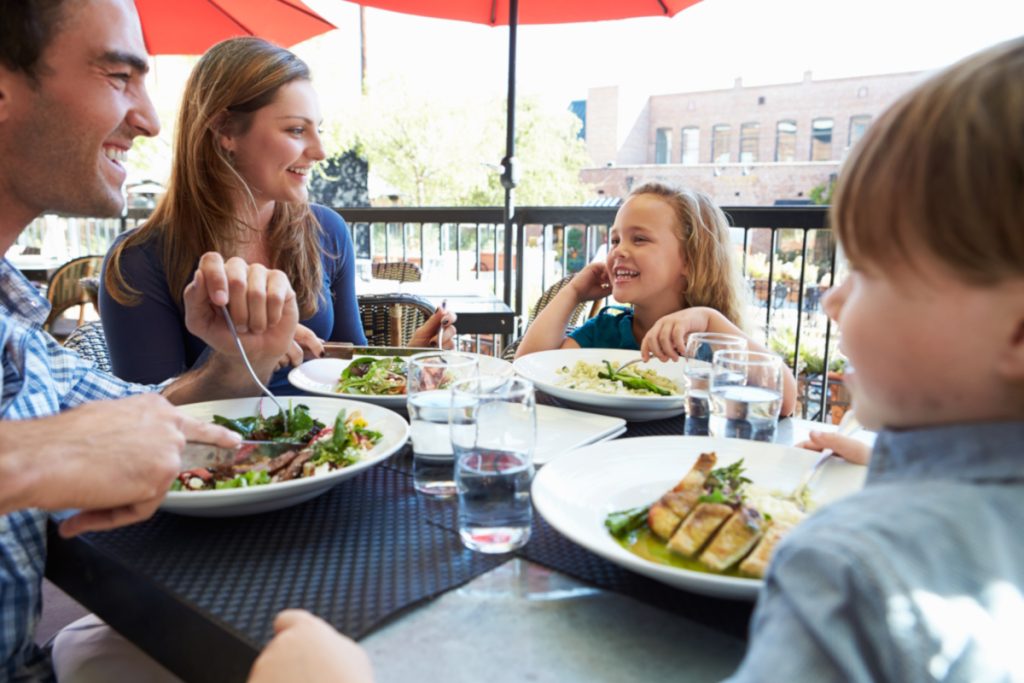 Family Enjoying Meal At Outdoor Restaurant to Travel Green