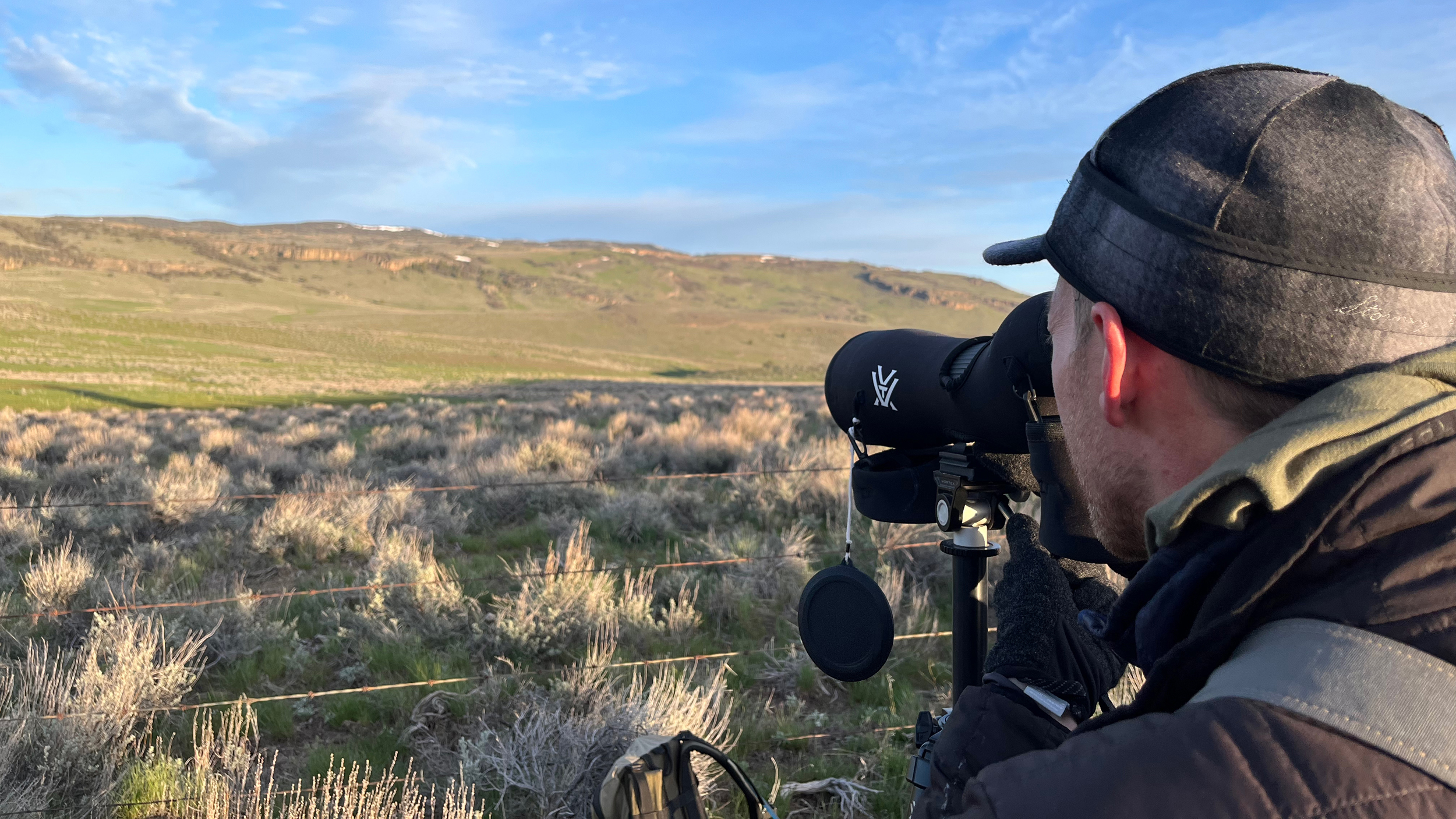 Skyler Vold spots sage grouse through his spotting scope as they conduct their mating dances at a lek in Oregon on April 23. Credit: Wyatt Myskow/Inside Climate News