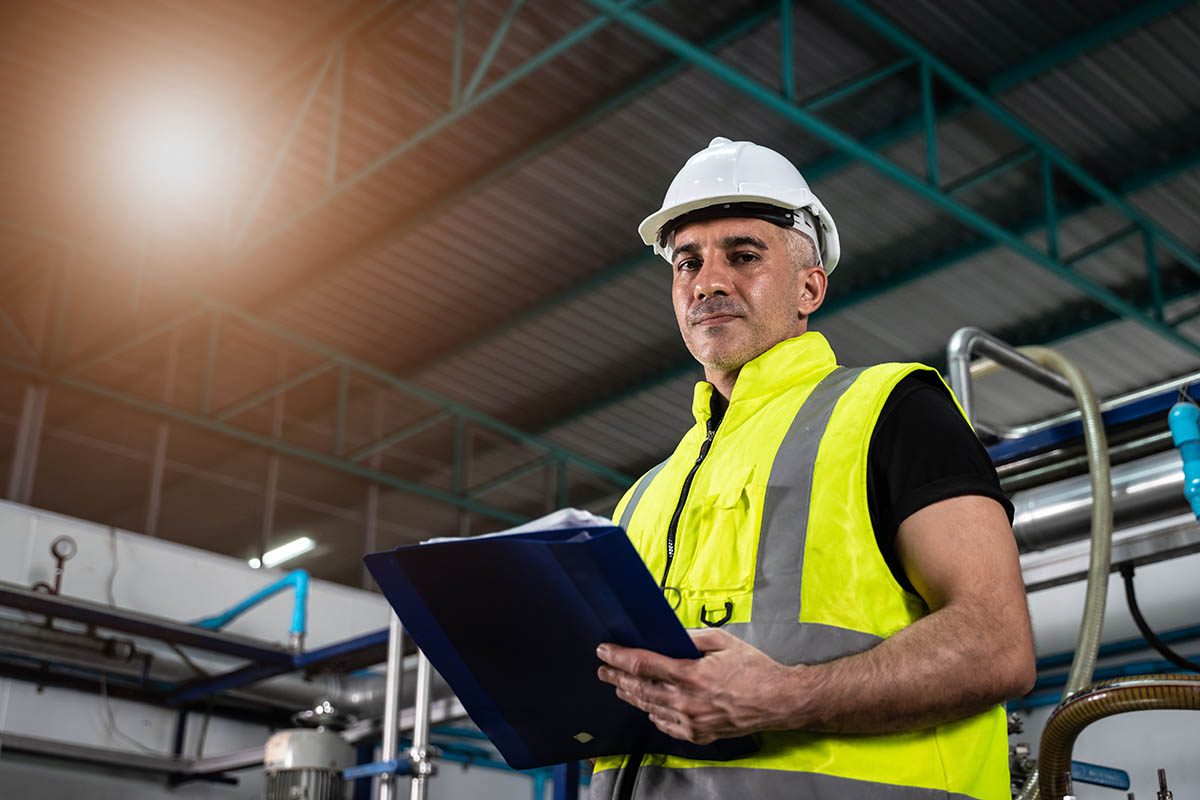Engineer or construction worker, holding a tablet, looks towards the camera, which is positioned below him and at an angle