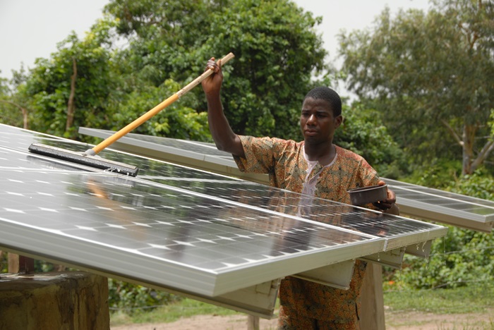 A solar technician from SELF’s local NGO partner washes panels in the village of Dunkassain northern Benin.