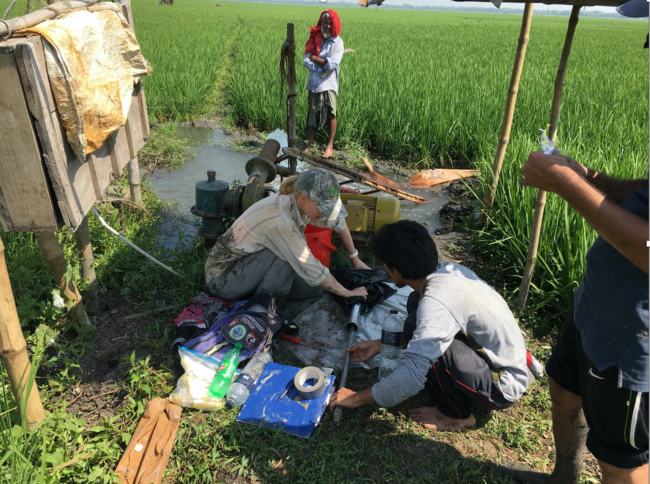 Liz Chamberlain collects a sample of mud from the abandoned Ganges River channel for optically stimulated luminescence dating. In the background, a pump delivers groundwater to irrigate rice which is often cultivated in relatively low elevation areas of the Ganges floodplain, Bangladesh.