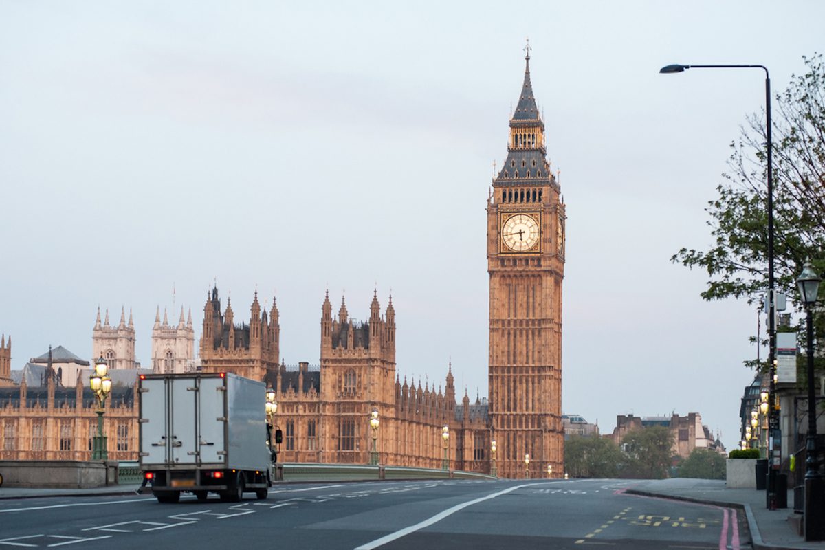 A white truck crossing Westminster Bridge in London, with House of Commons in view