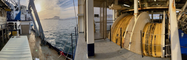 Panorama of the Langseth and its multichannel streamer reels with mountains along Mexican coastline in the background. 