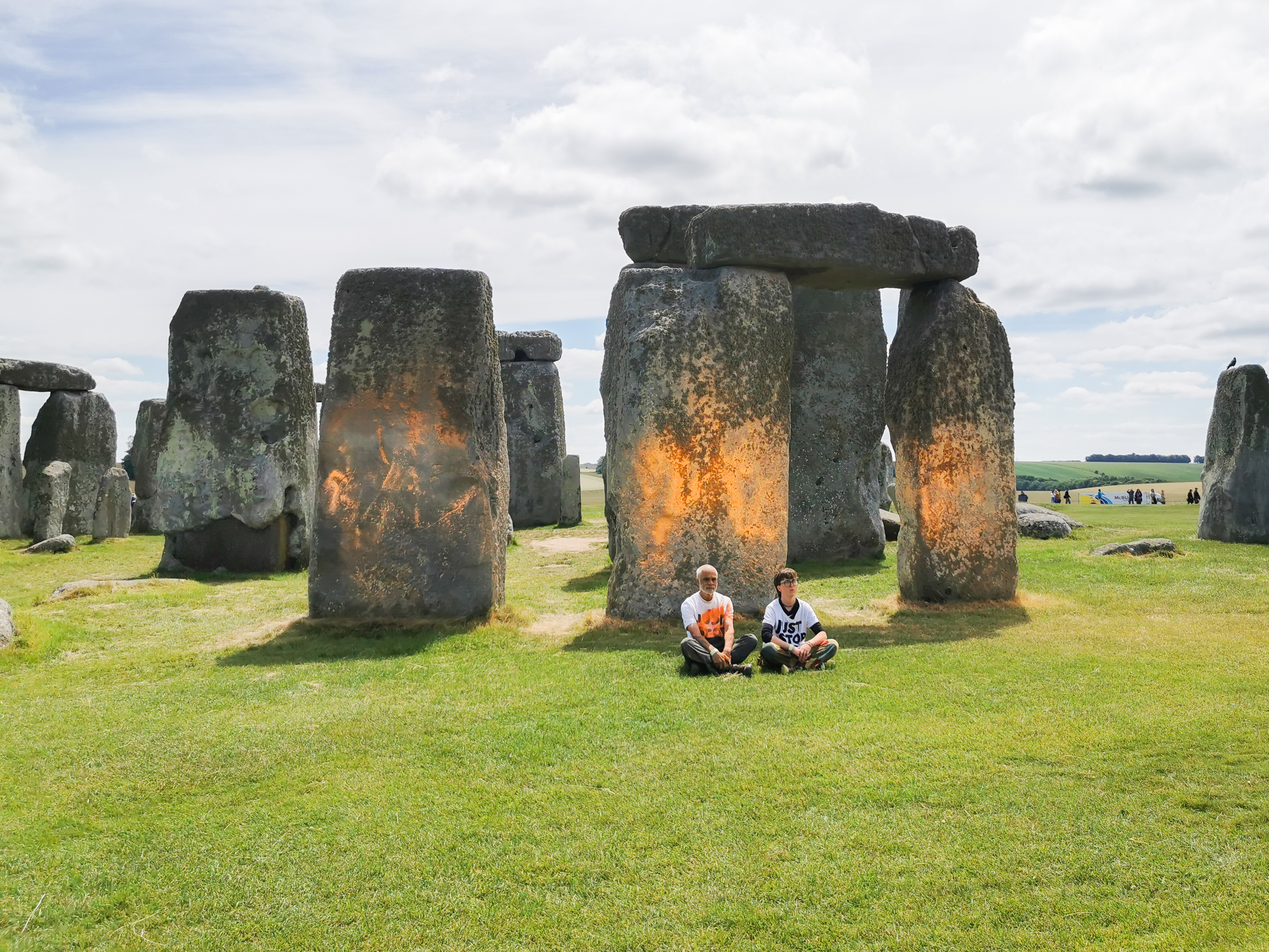 Just Stop Oil protesters sit in front of Stonehenge after dousing it with orange paint.