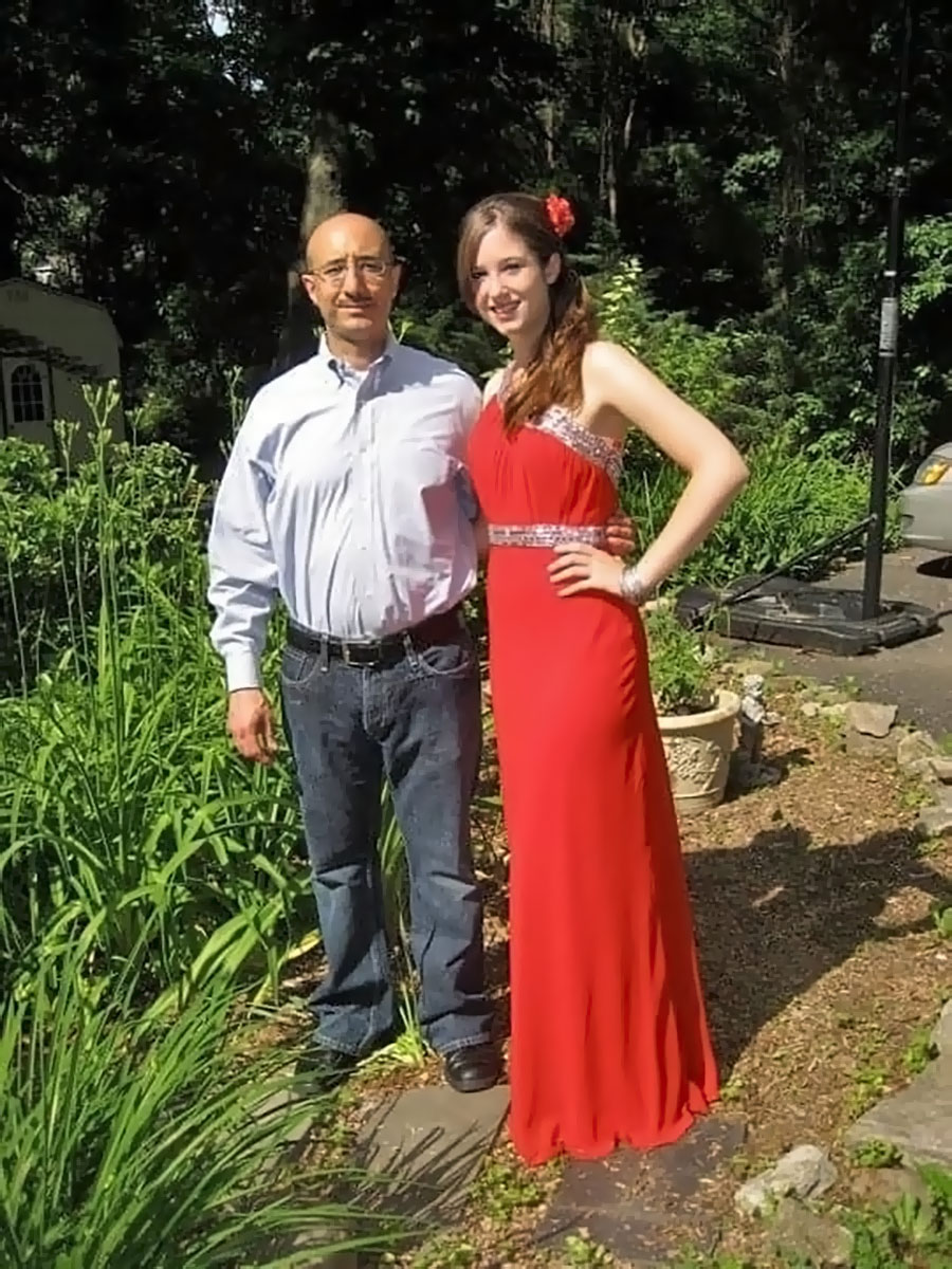 A girl in a red prom dress standing next to her father