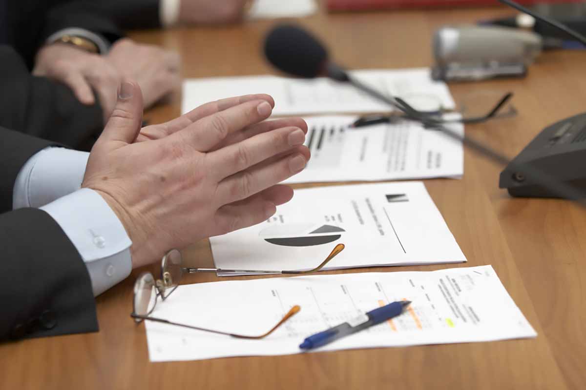 Close up of a meeting with microphone and papers on the desk.